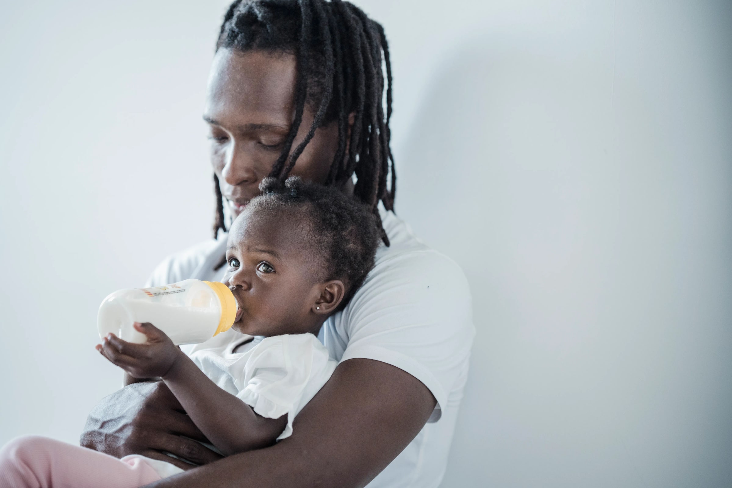 A father feeds a baby with a bottle.
