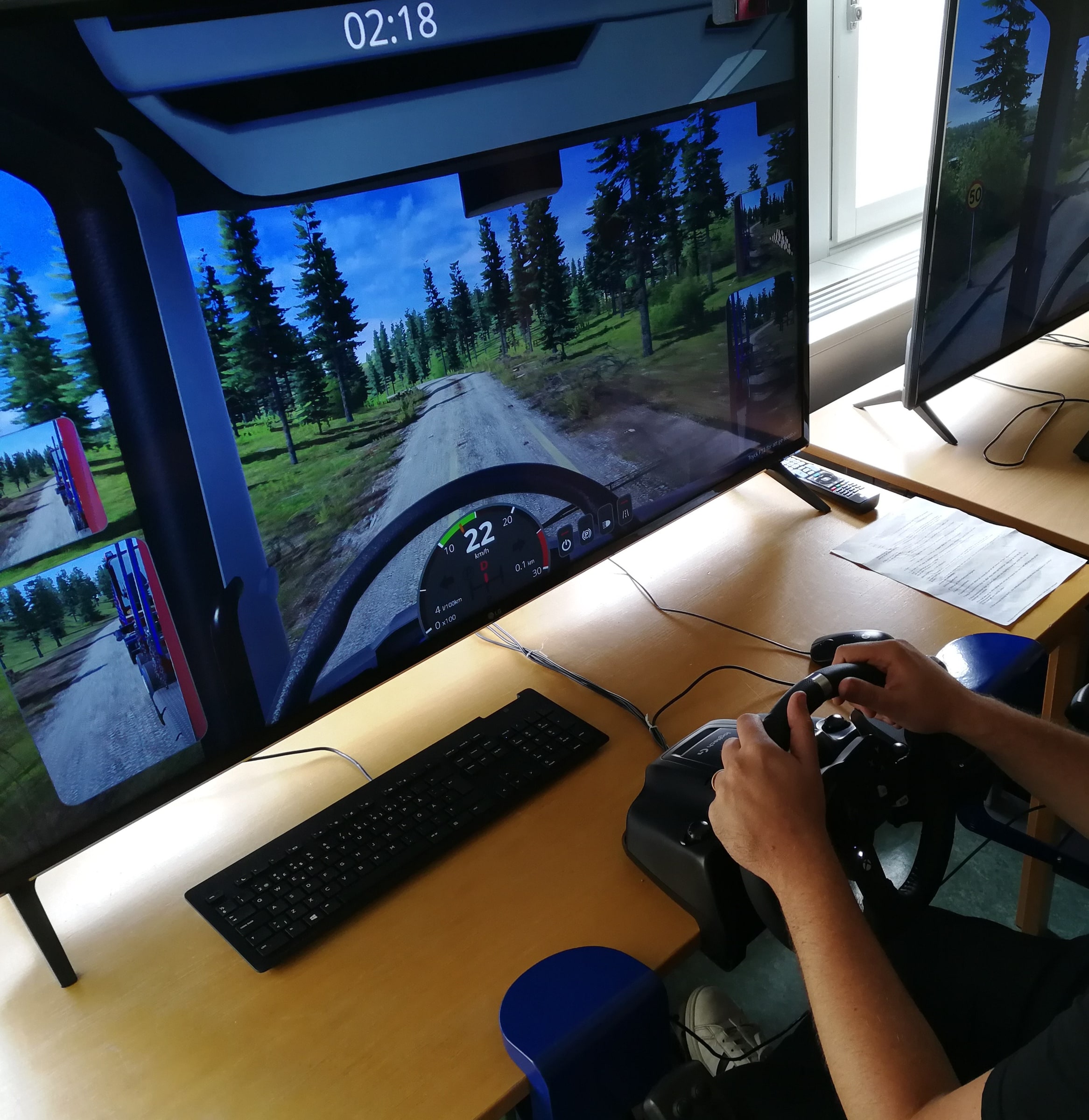 Hands operate a truck-driving simulator at Bråvallagymnasiet in Norrköping.