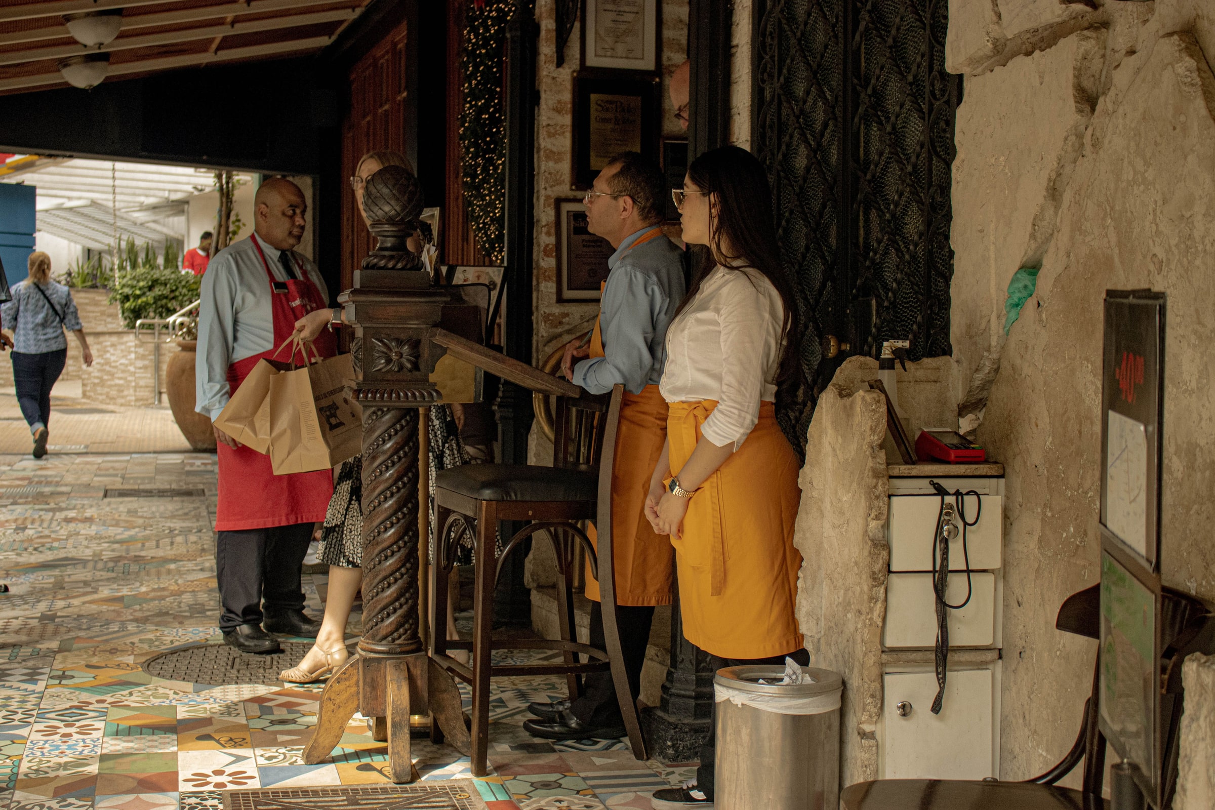 Restaurant staff greet customers at the entrance to a dining room.