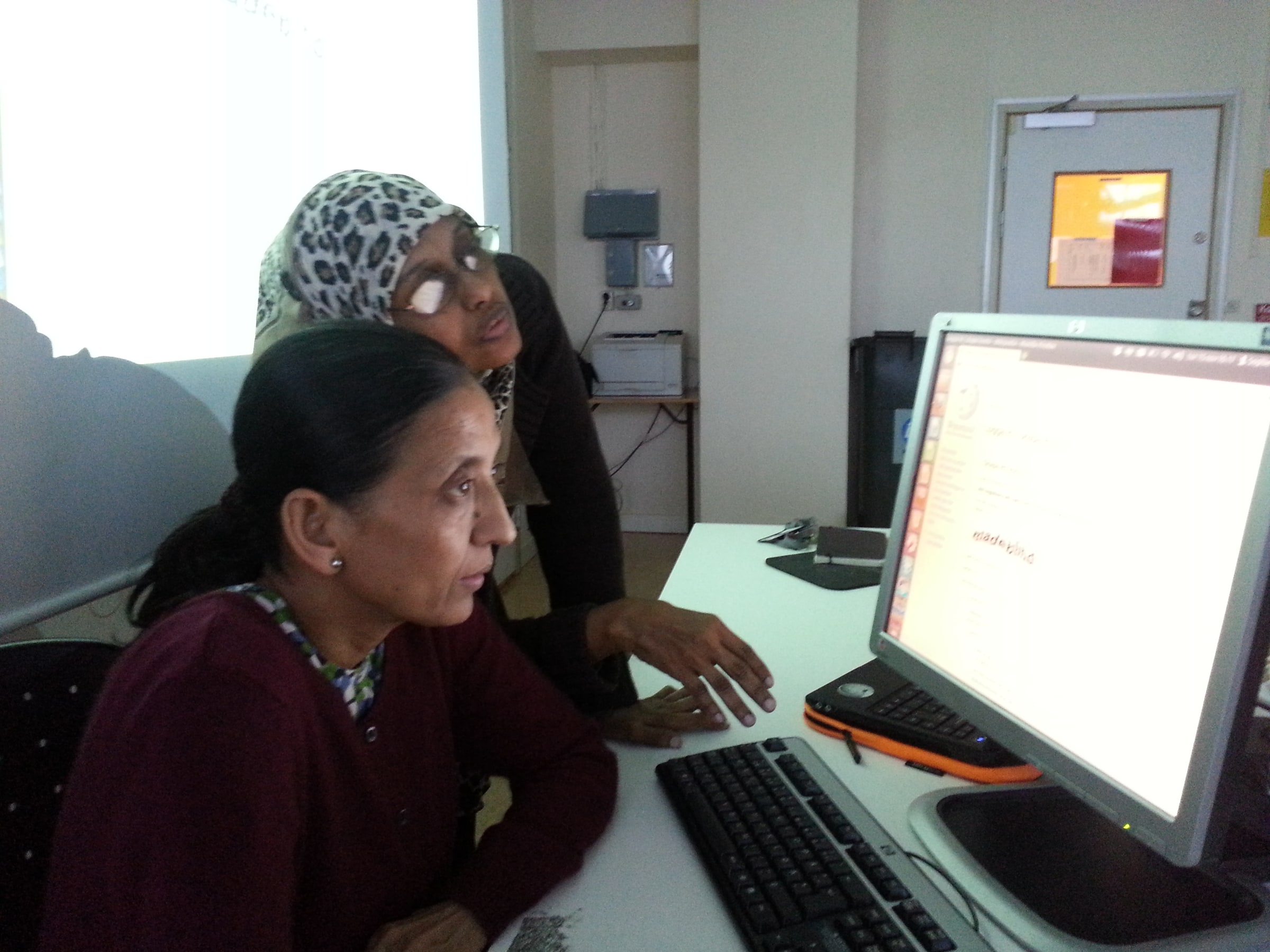 Two adults work together at a computer during a Swedish-language workshop in November 2012.