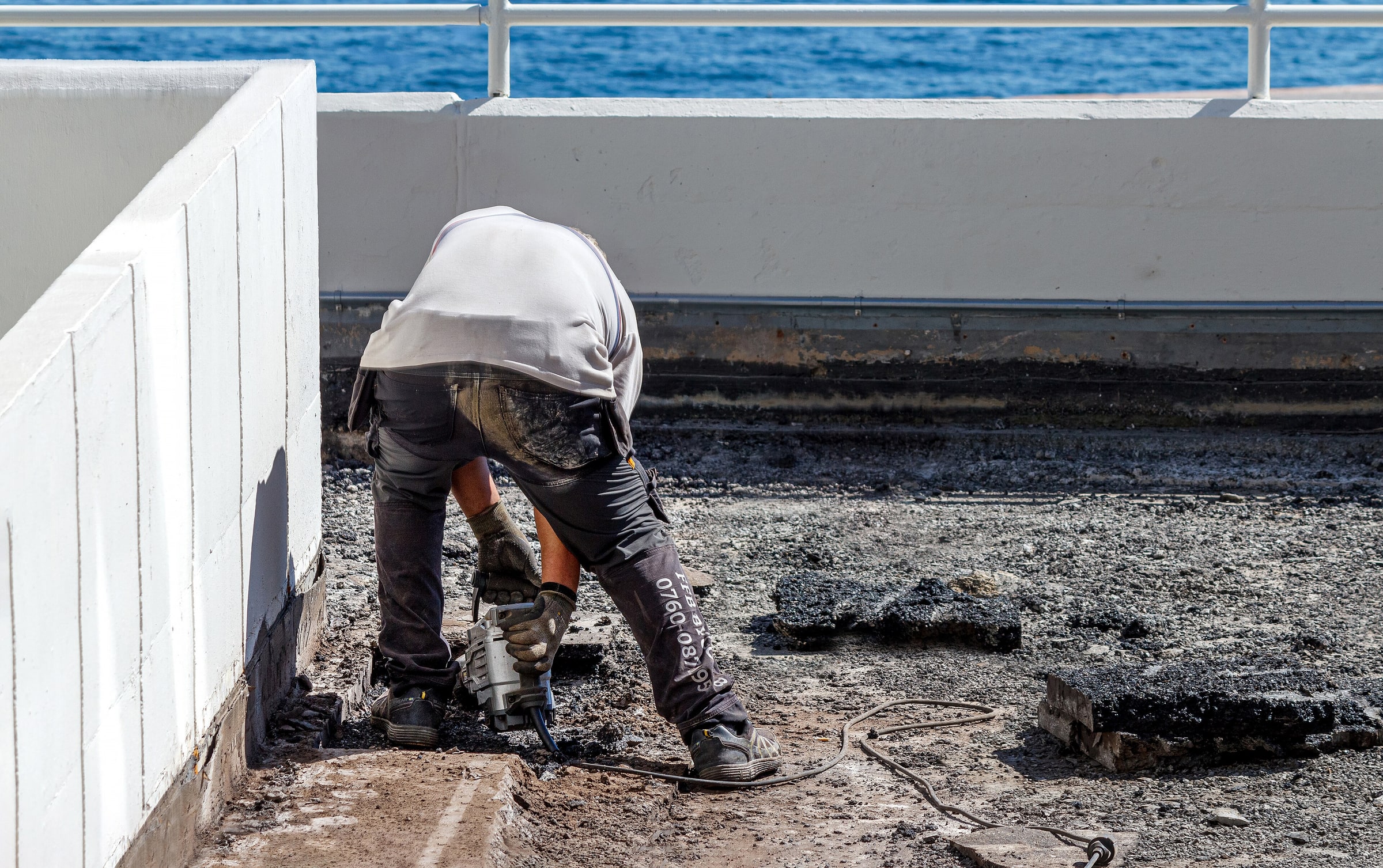 A worker operates an electric jackhammer on broken asphalt in Lysekil.