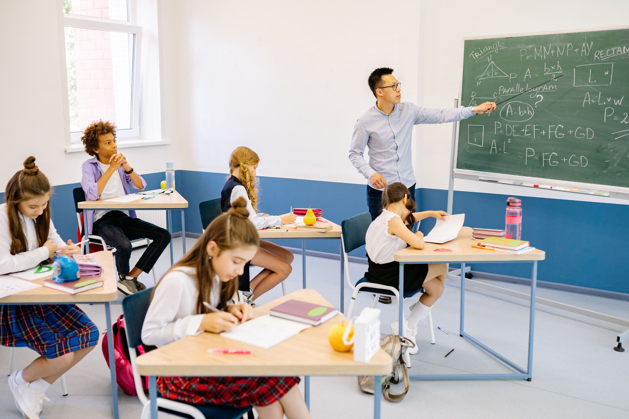 A teacher leads a maths lesson for pupils in a classroom.