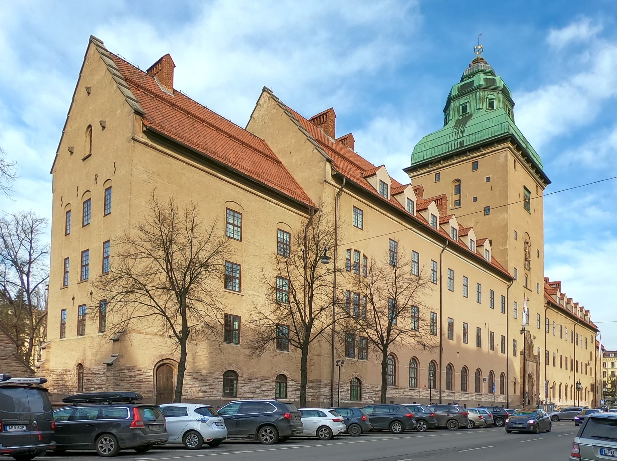Stockholm Court House’s brick and stone facade, green roof and arched entrances beside a street.