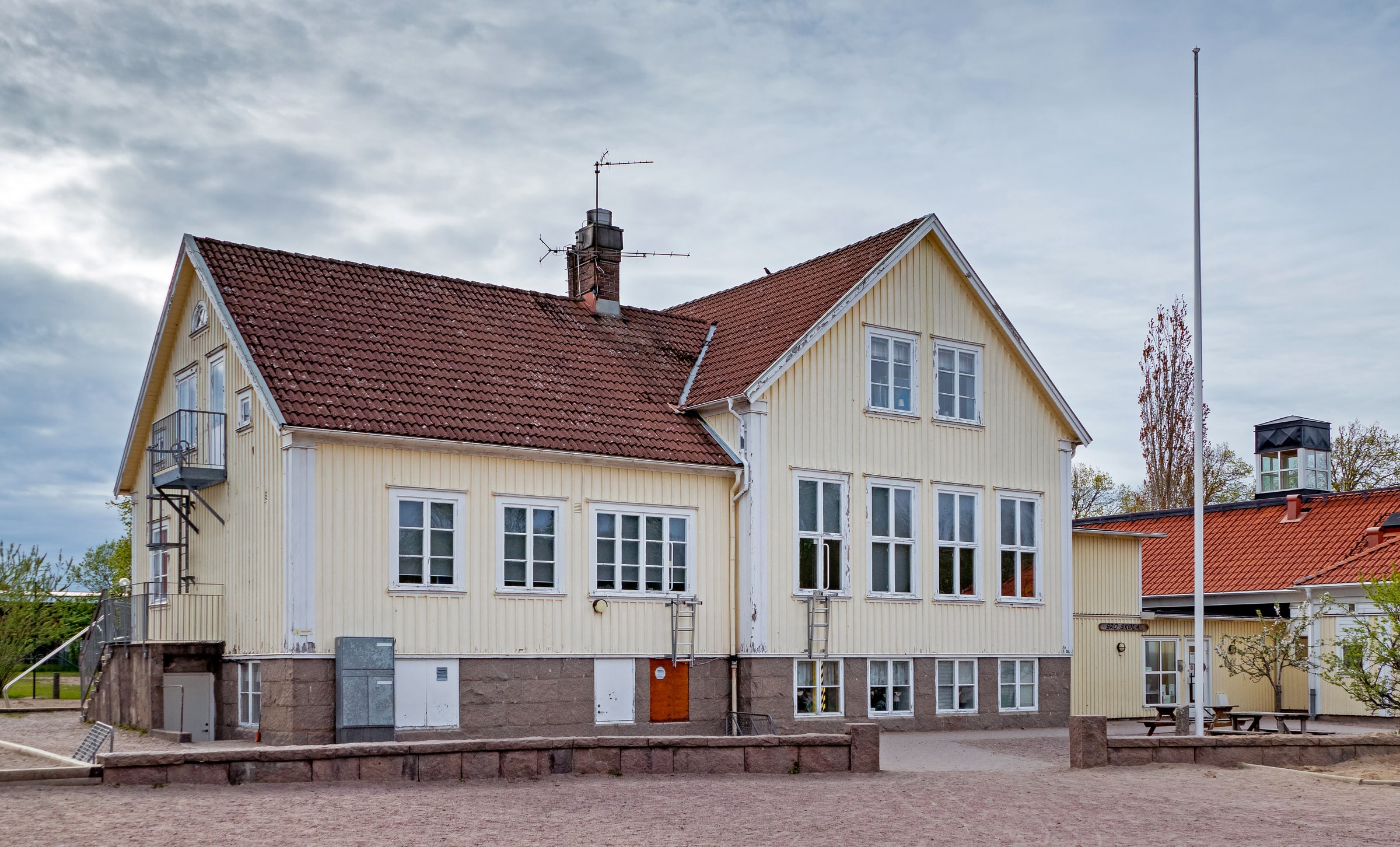 Yellow timber Bro school building with red roof and classroom windows in Brodalen.