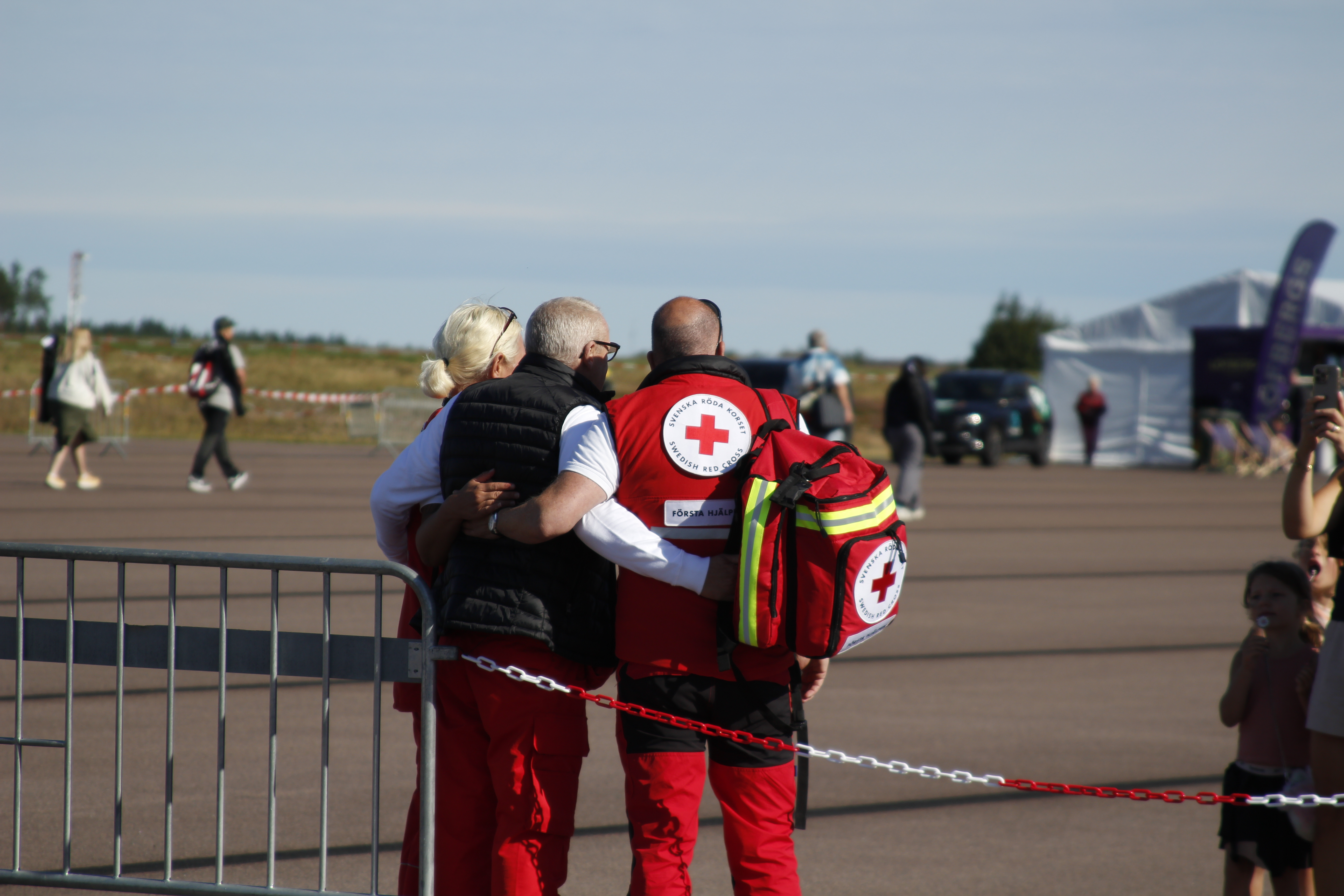 Three Swedish Red Cross volunteers stand together with first-aid bags at Karlstad Airport.