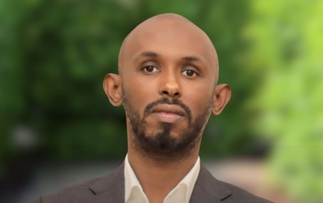 Mohamed Abdukardir Ali wearing a suit against a green background.