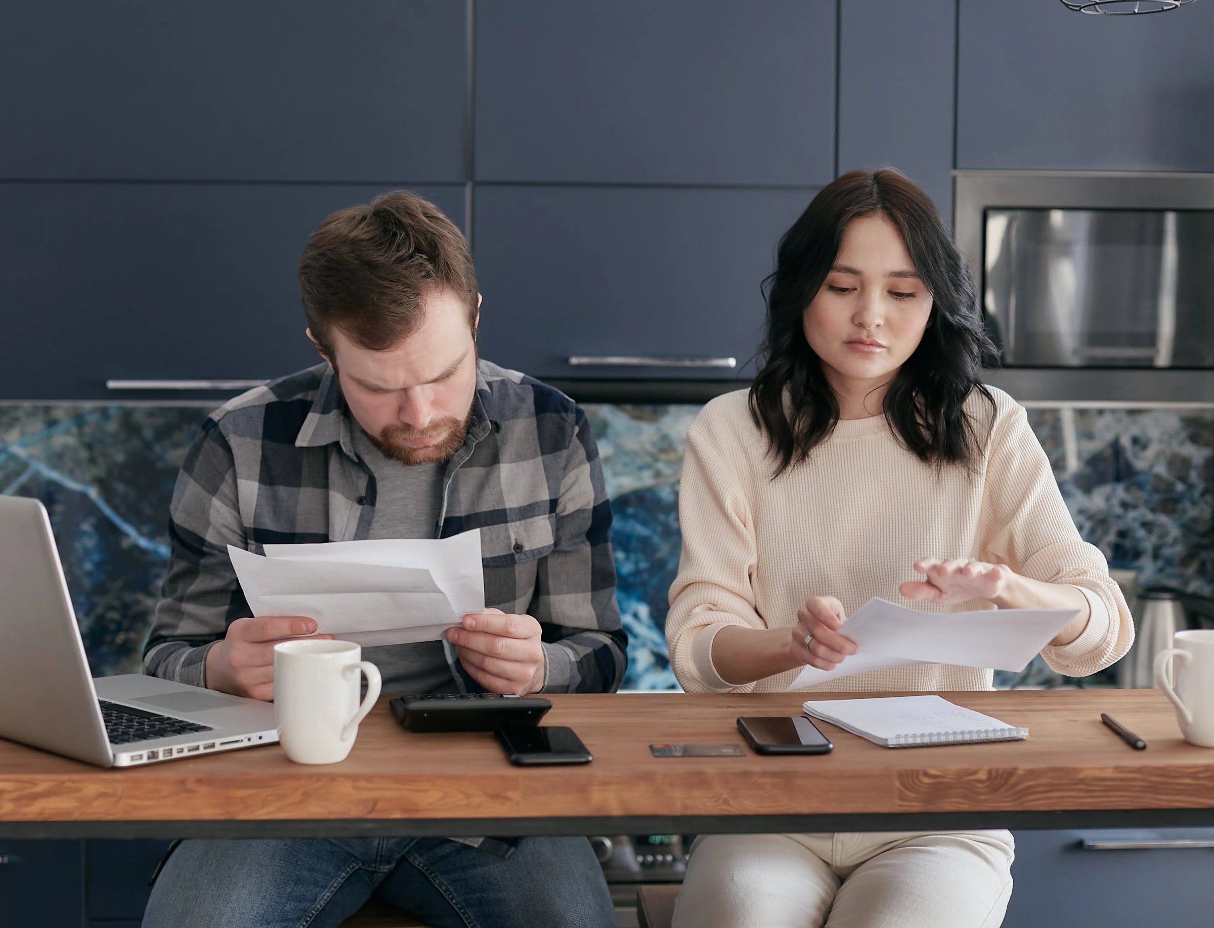 Two adults read documents at a kitchen table.