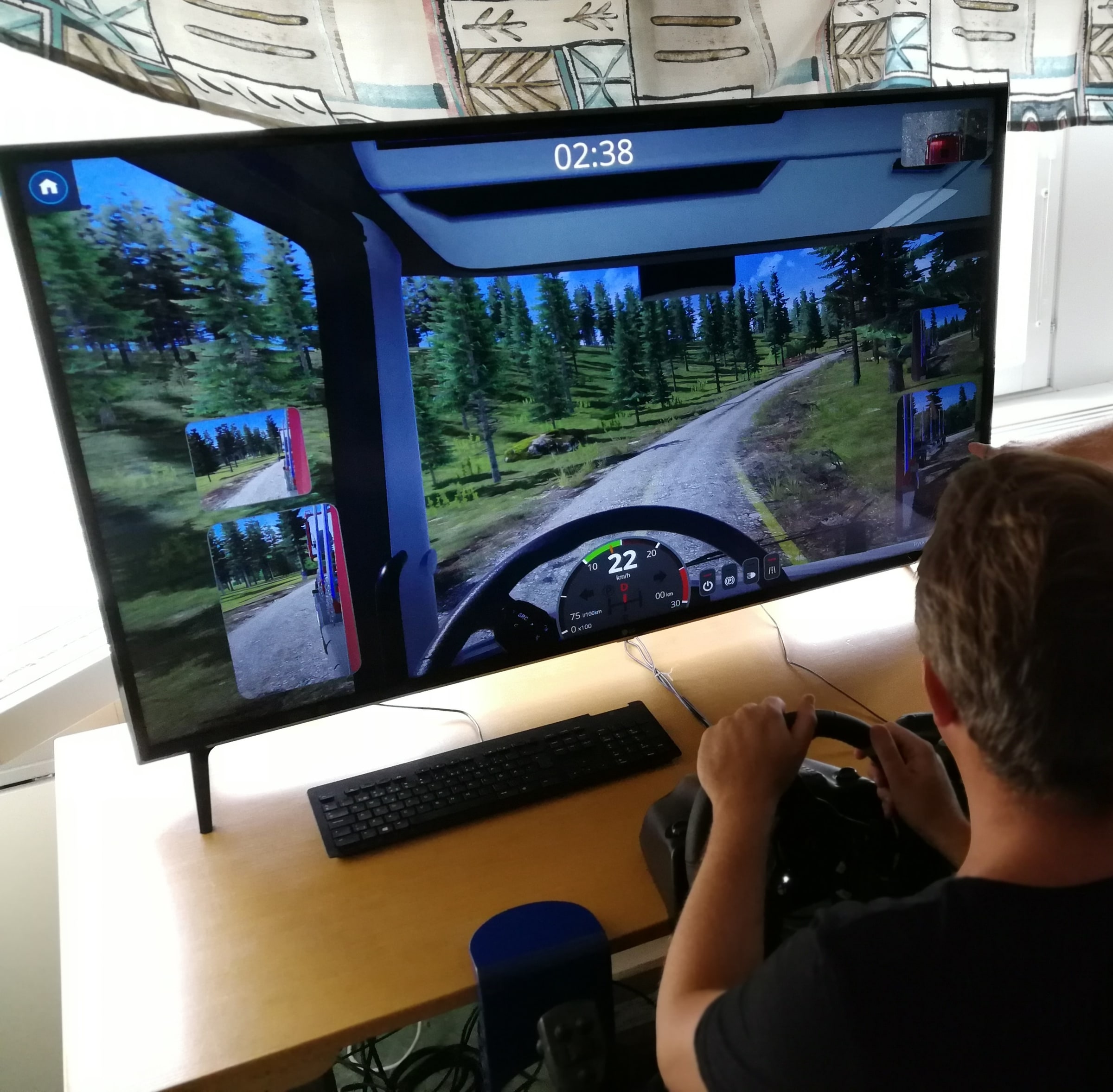A learner holds a steering wheel in front of a truck-driving simulator at Bråvallagymnasiet.