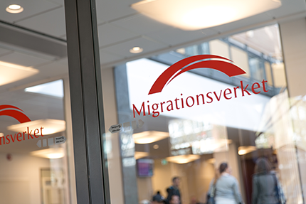 The red Migrationsverket name and bridge symbol displayed on a glass office wall.