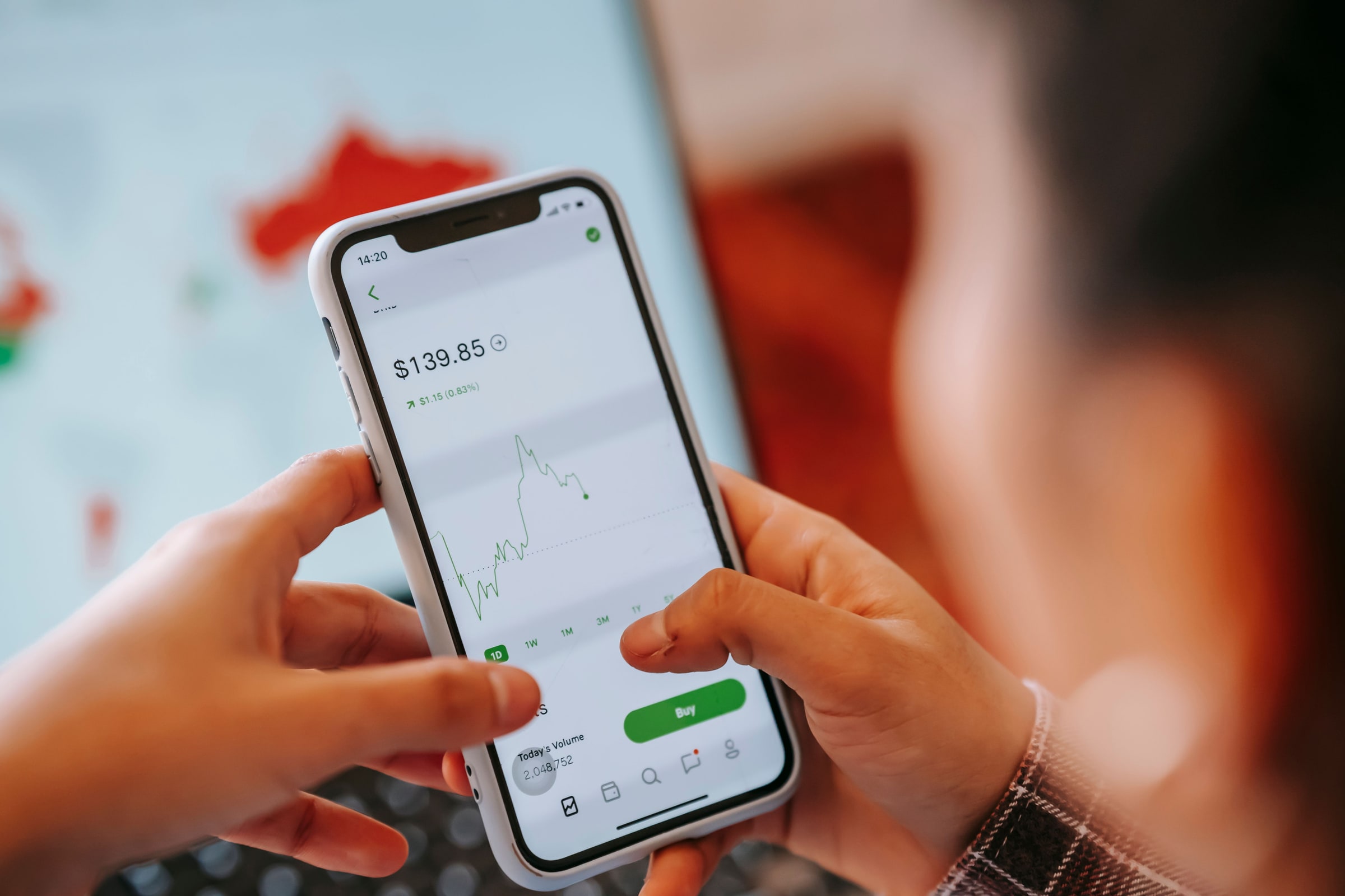 Anonymous hands use a smartphone displaying a market-price chart.